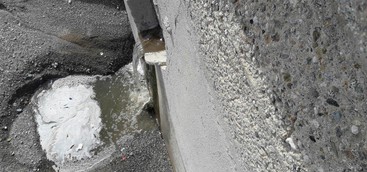Liquido schiumoso e maleodorante versato sulla spiaggia da tubo di acqua piovana